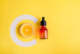 Vitamin С Glass bottle and orange on a yellow background