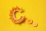 Plate in shape of letter C with orange slices on bright yellow background